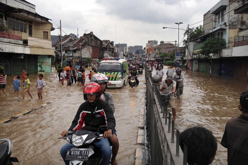 Locals make their way through floodwaters in Jakarta.