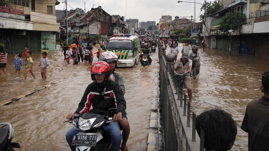 Locals make their way through floodwaters in Jakarta.