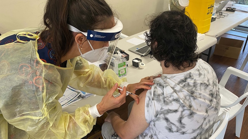 A nurse injects a vaccine into the arm of a patient.