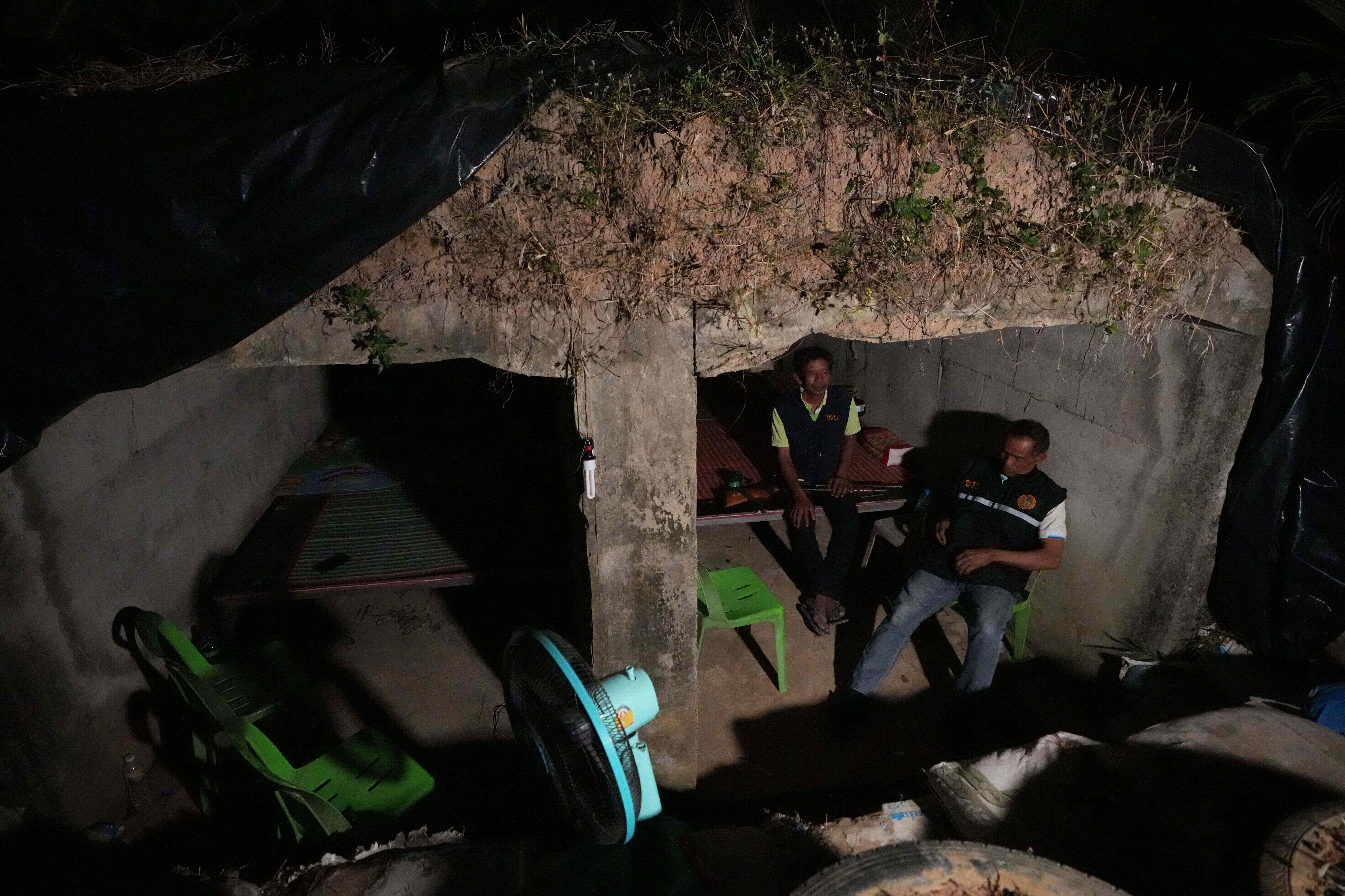 Dos hombres se sientan en sillas de plástico en un refugio de animales por la noche.