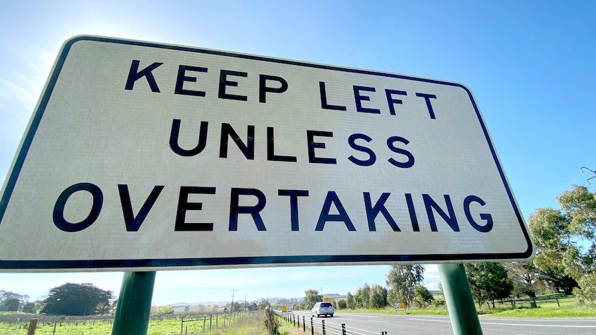 A sign on a road that says keep left unless overtaking.