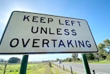 A sign on a road that says keep left unless overtaking.