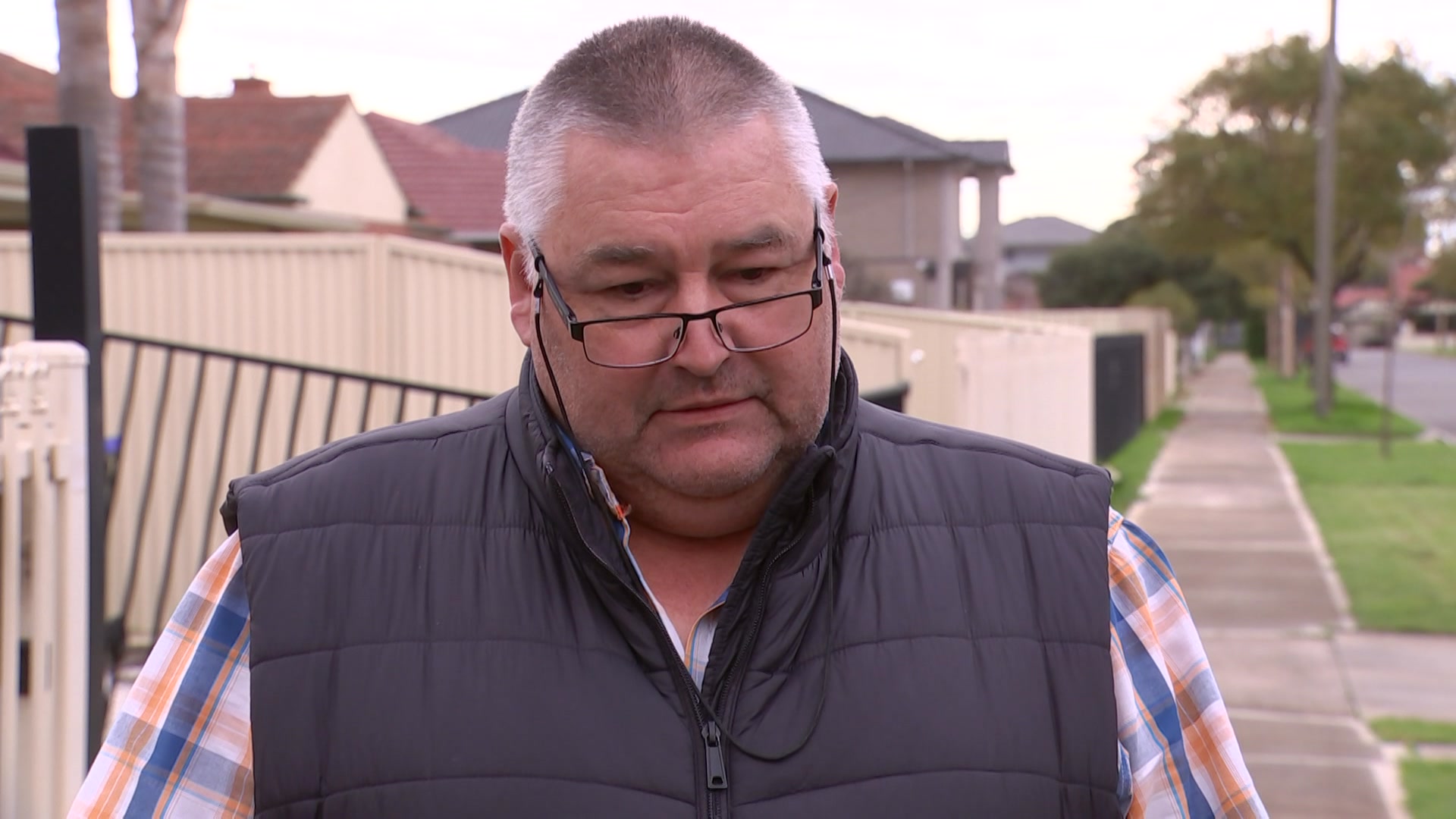 man standing in vest with checkered shirt and glasses