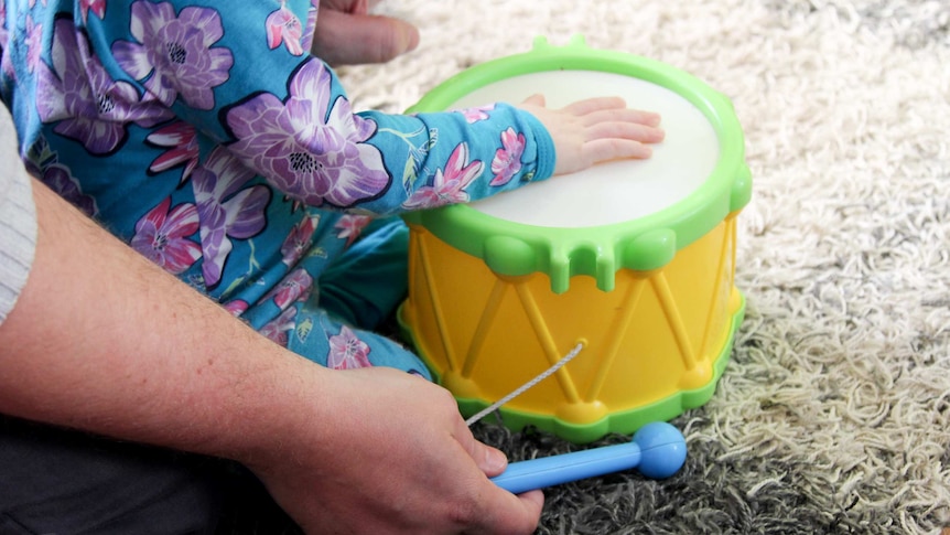 Child playing a toy drum.