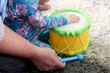Child playing a toy drum.