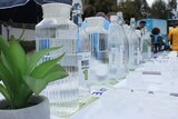 Bottles of water with plastic cups ready for tasting.