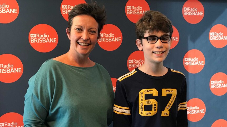 presenter Rebecca Levingston and 13-year-old Joshua Wood stand smiling in the ABC Radio Brisbane studio.