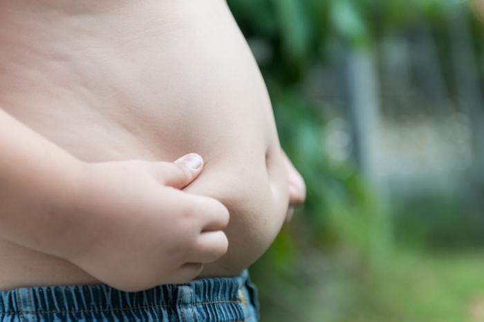 An overweight child holds his hands to his stomach