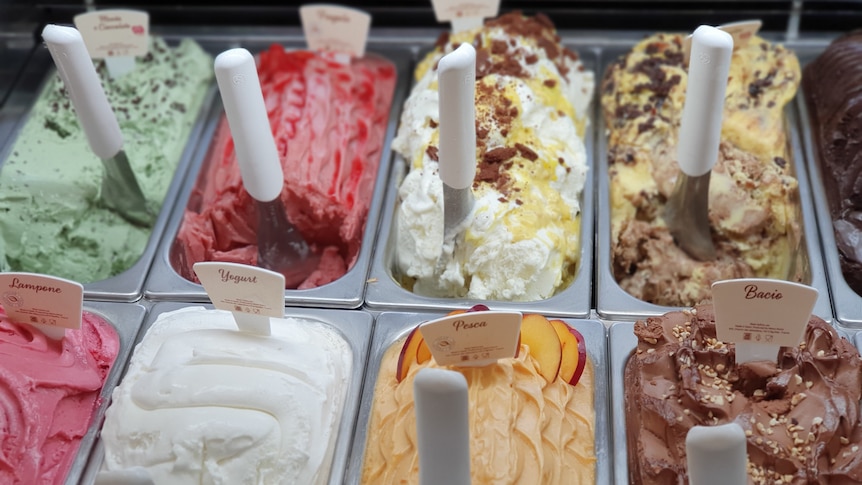 An array of ice cream or gelato tubs in a store window.