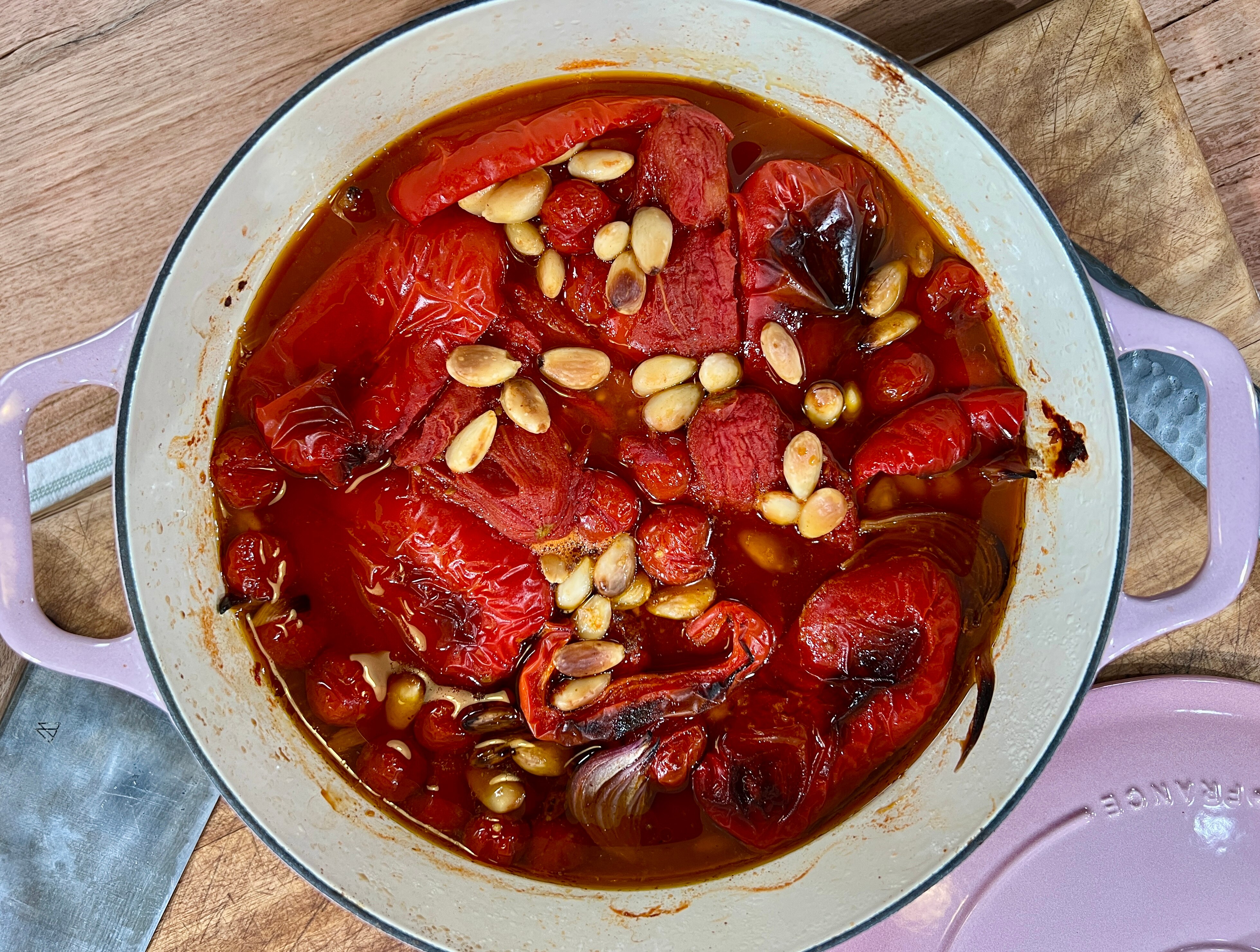 A picture of capsicum, onion, almonds and stock roasting in a saucepan.