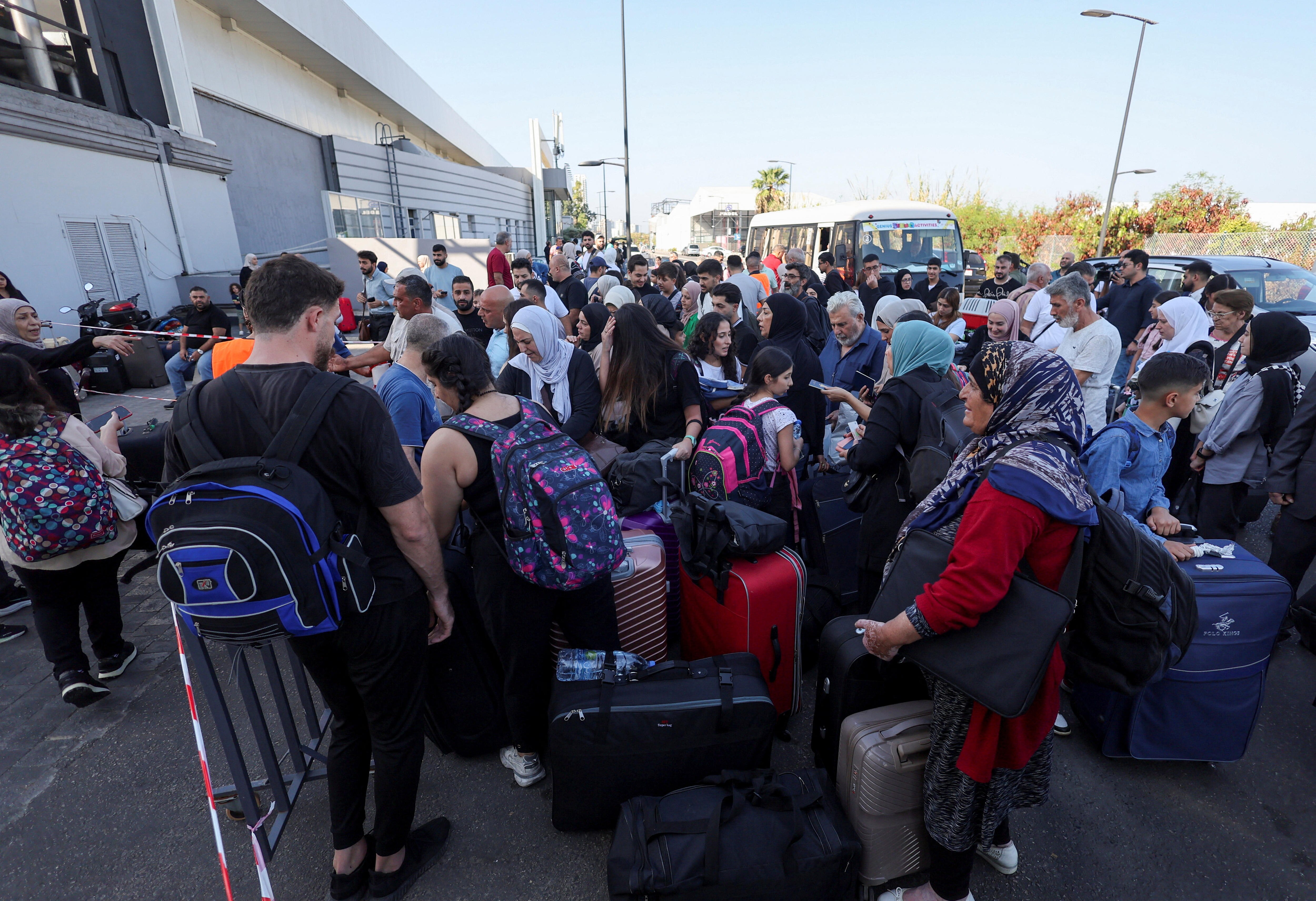 A crowd of people in front of a building and bus.