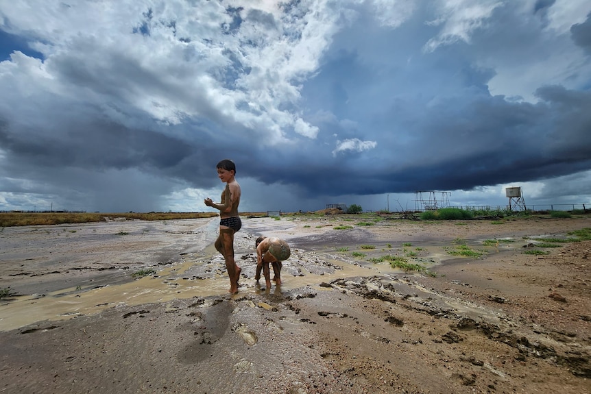 Boys play in mud after rain in western Queensland