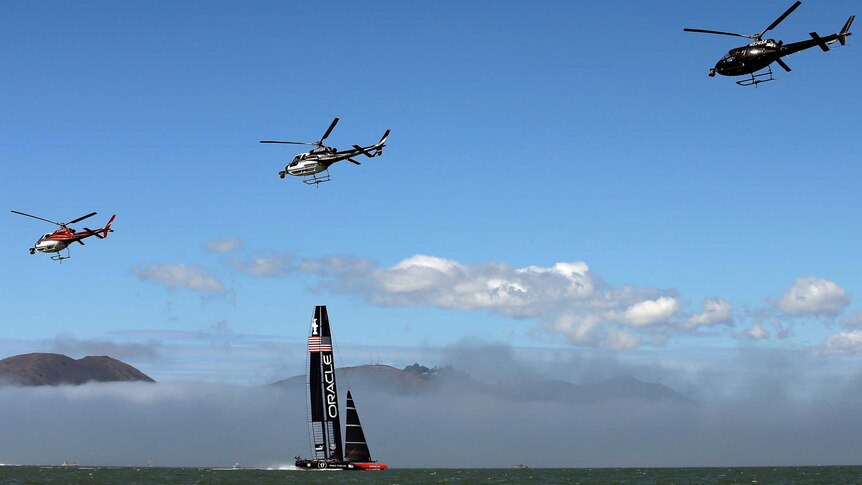 Helicopters fly over Oracle Team USA as it warms up before a race during the America's Cup finals.