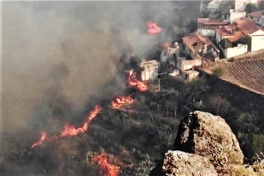 A shot from above showing fires and smoke near homes.