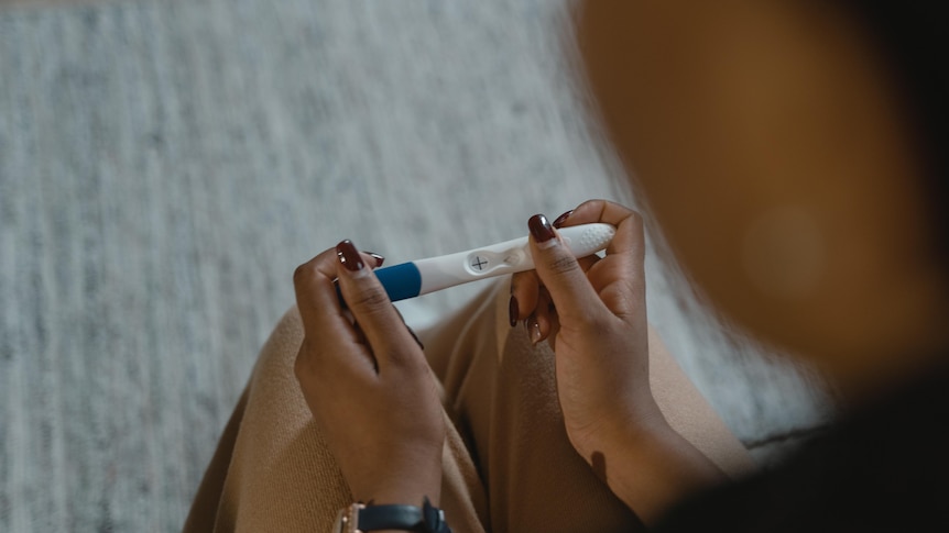 An unidentified woman looks at a positive pregnancy test.