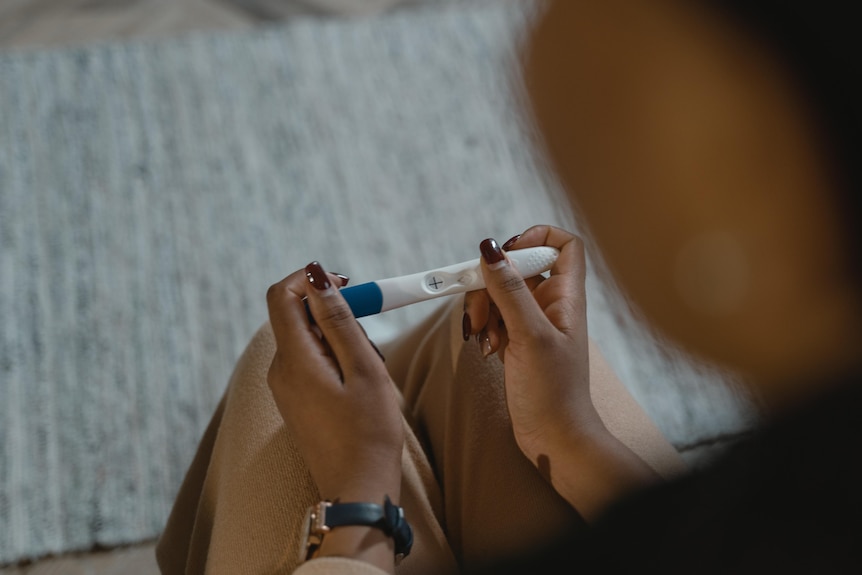 An unidentified woman looks at a positive pregnancy test.