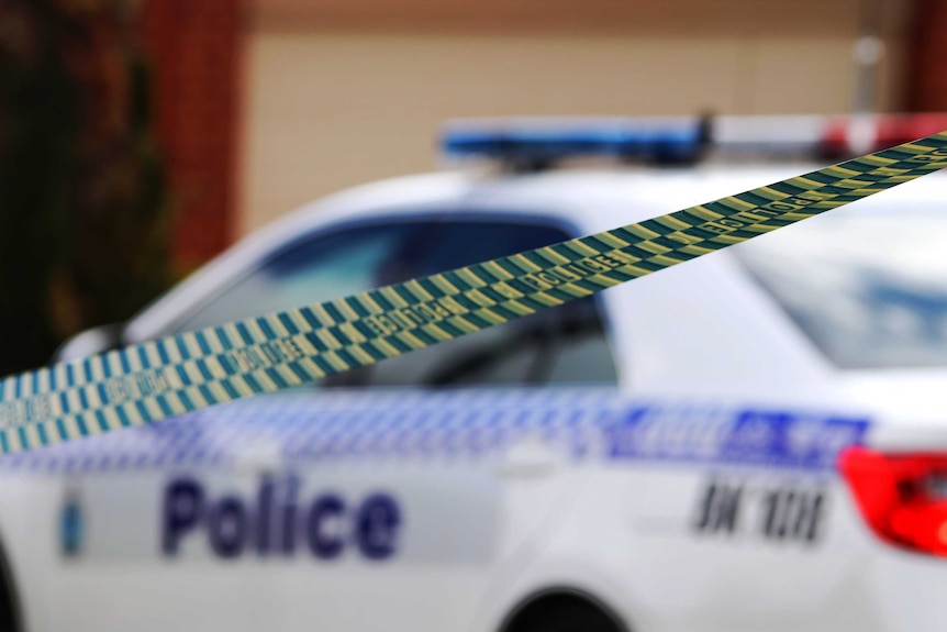 A crime scene with WA Police tape in the foreground and a police car in the background.