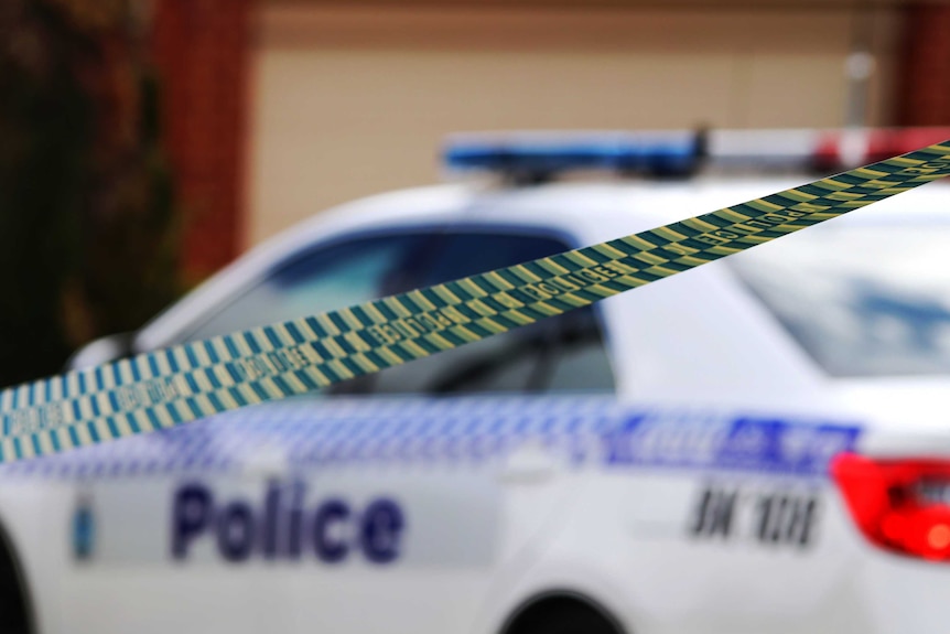 A crime scene with WA Police tape in the foreground and a police car in the background.