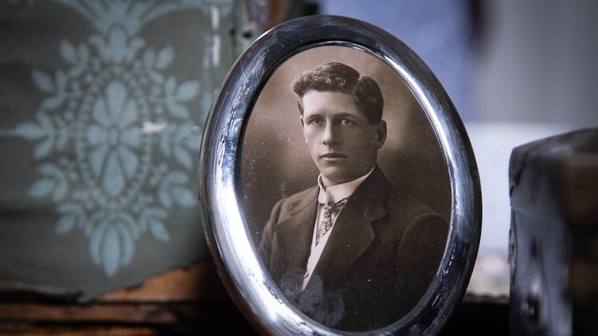 A black and white framed photograph of a young man in a suit.