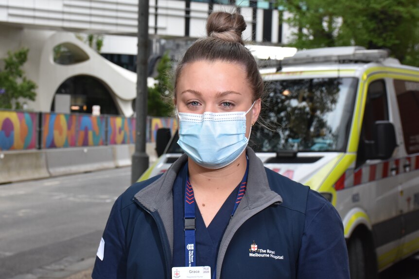 A woman wearing nursing scrubs and a face mask.