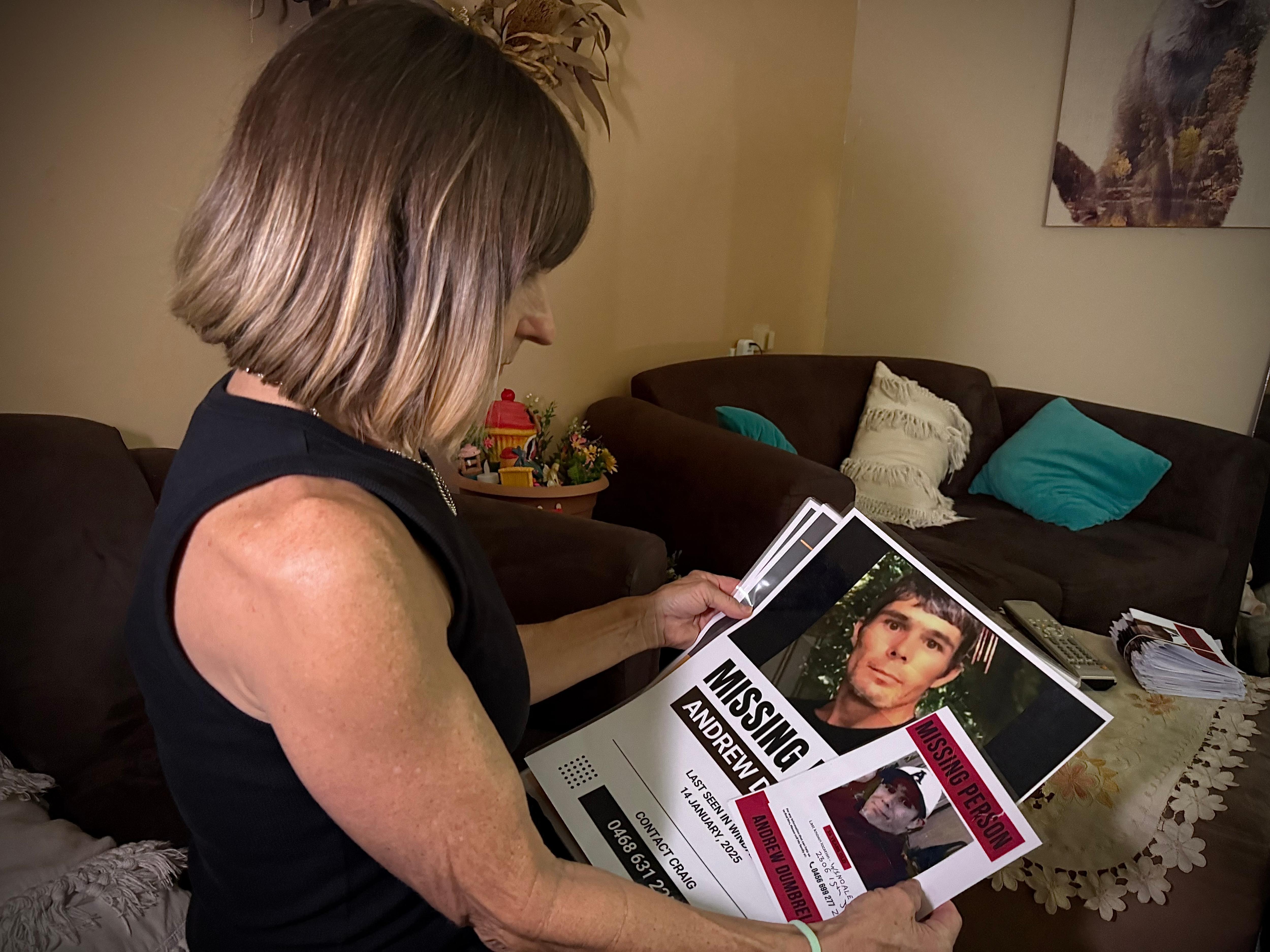 Angela Jackson, el marido de Andy, mira fotografías de hombres desaparecidos en el salón.