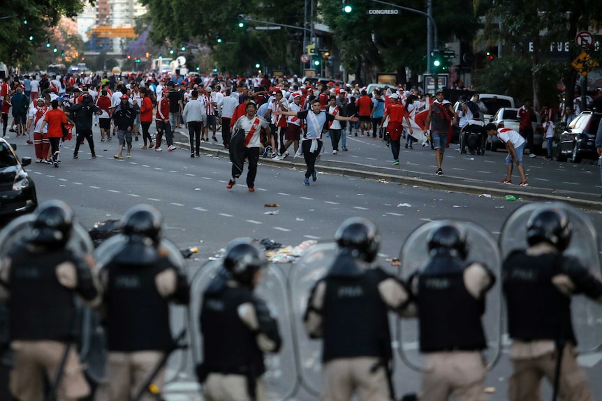 Riot police watch River Plate fans approach