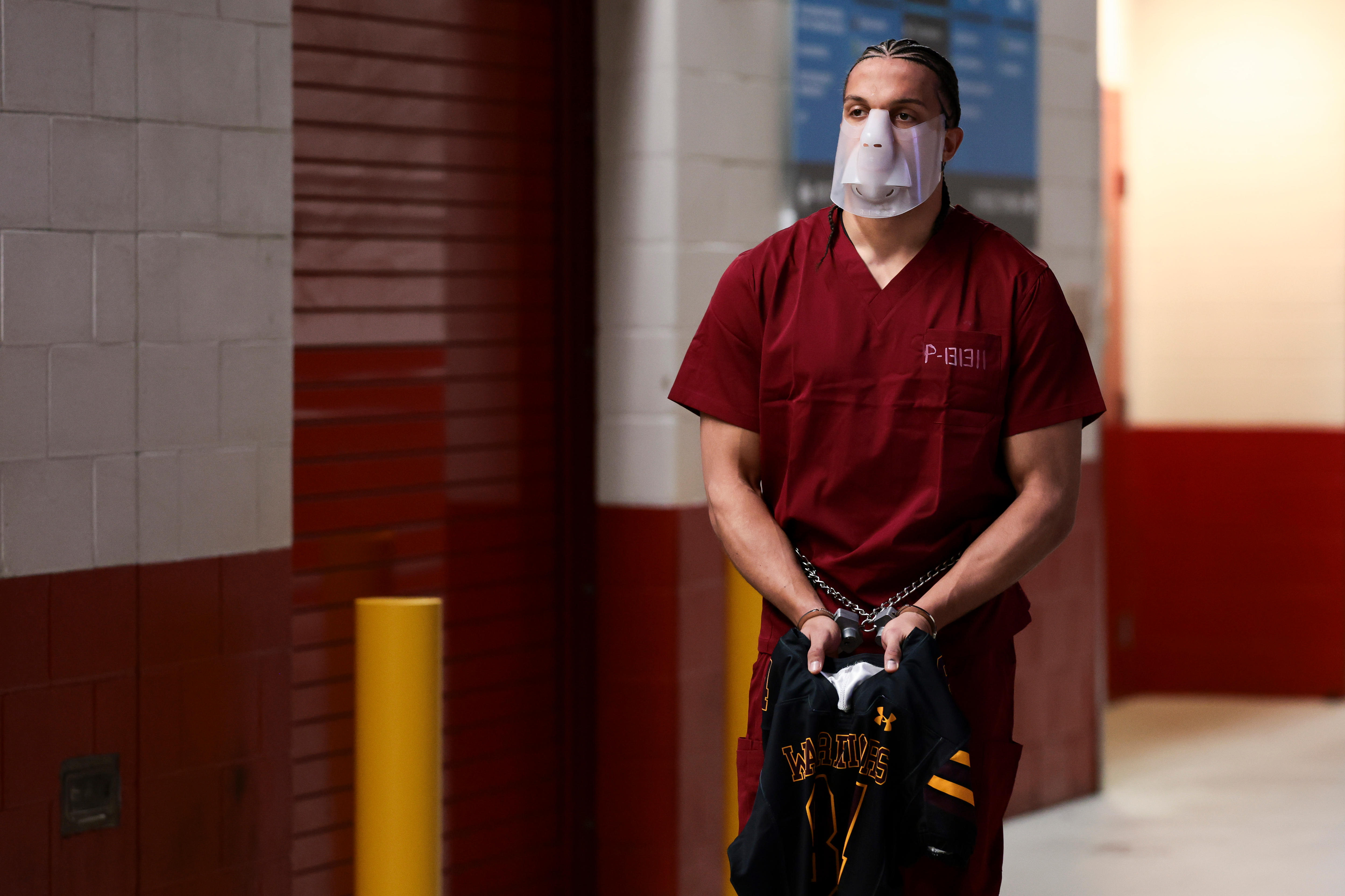 A man wears a face mask and some chains on his arms.