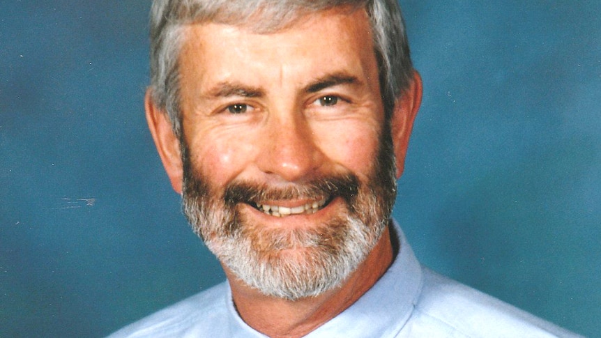 photograph of man in tie and blue shirt smiling