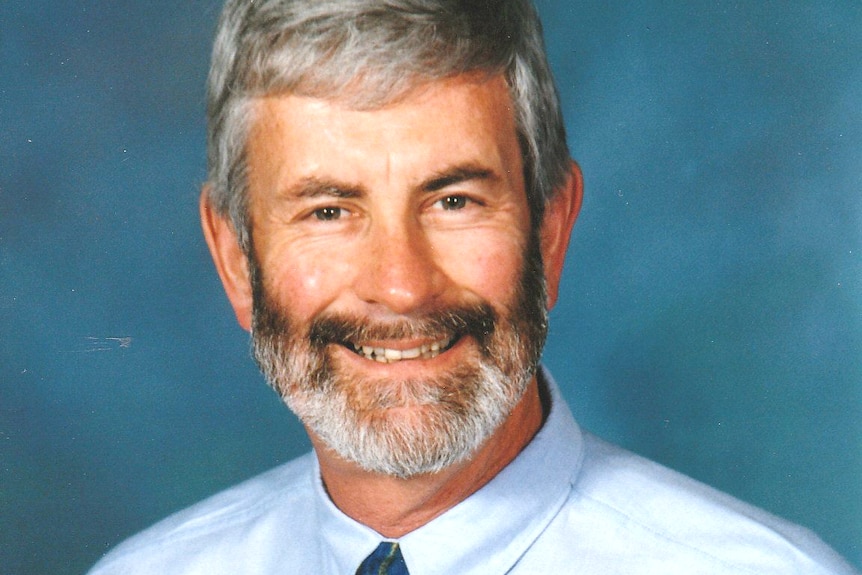 photograph of man in tie and blue shirt smiling