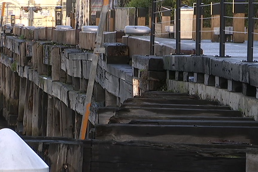 Planks of wet and deteriorating wood line the Central Pier at the edge of the water.