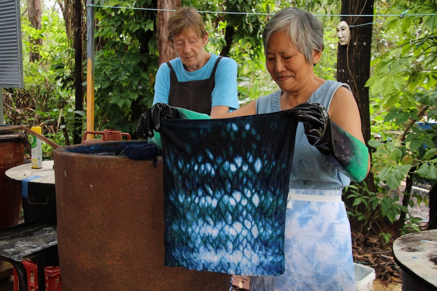 Two women dye fabric with indigo.