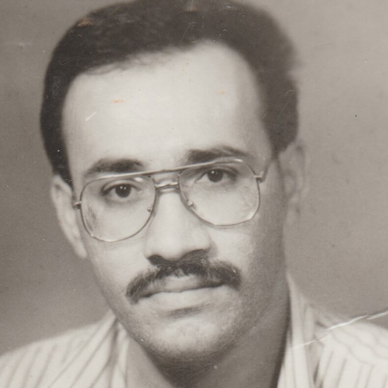 A man with glasses and a moustache looks at the camera.