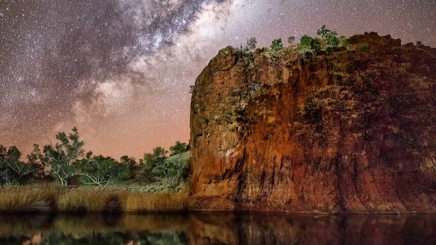 The Milky Way reflects in the waters of a gorge.