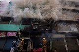 Firefighters try to douse a fire in a shop as smoke billows.