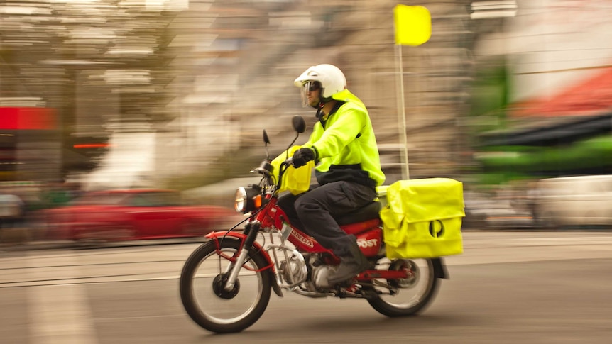 A postman from Australia Post delivers mail on a motorbike.