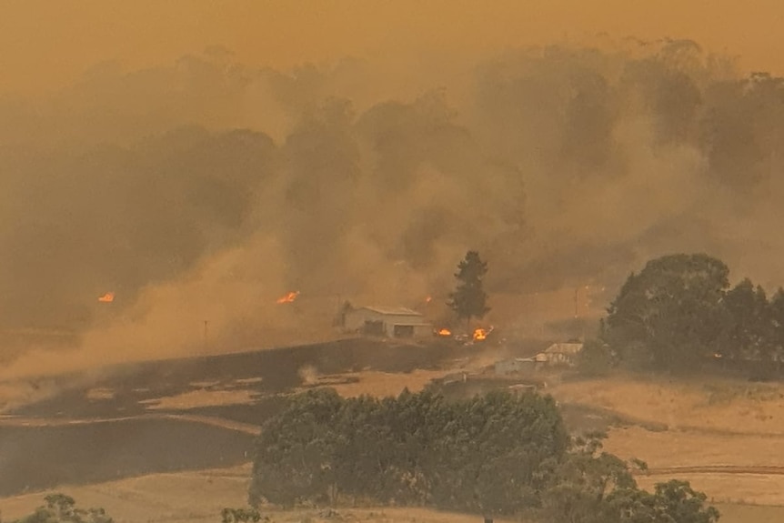 Fire burns near a building.