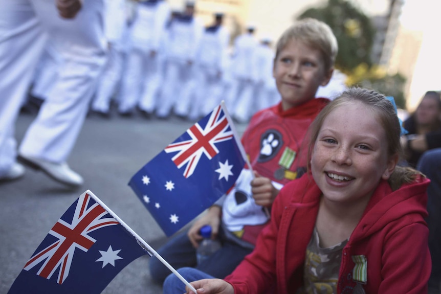 A young girl and boy holding Australian flags and watching the parade through Perth.