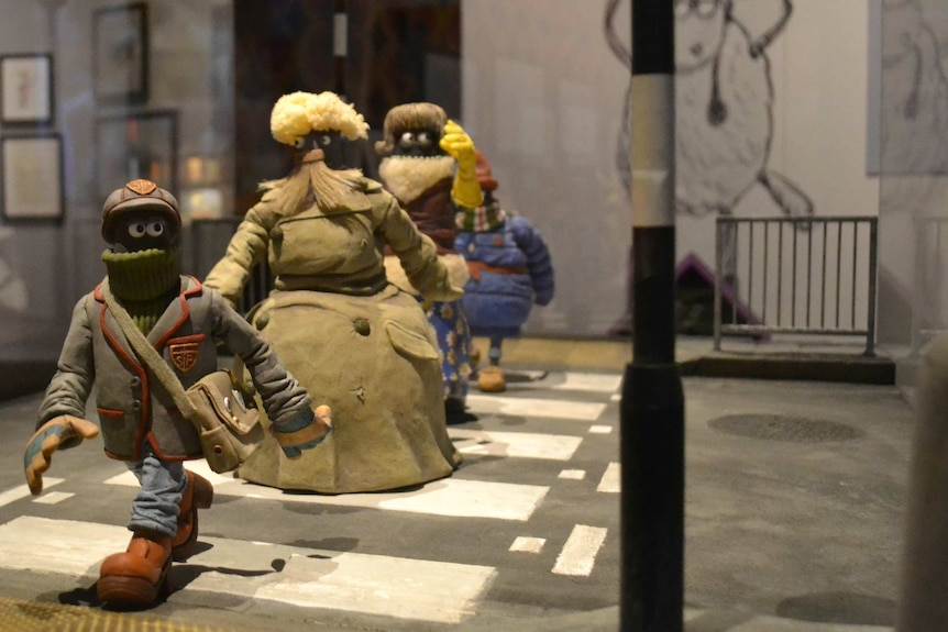 An assortment of characters off the back of Wallace and Gromit series crossing a claymation street.