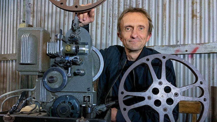 A man poses with a film projector