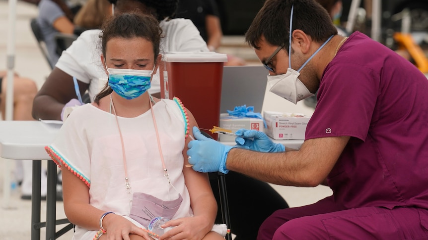 A young woman receives a vaccine shot from a nurse