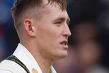 Marnus Labuschagne walks, holding his batting helmet under his arm, next to Steve Smith who is looking towards him