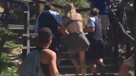 An 18-year-old woman is led away by Byron Bay police.