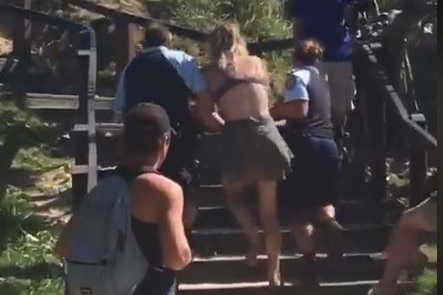 An 18-year-old woman is led away by Byron Bay police.