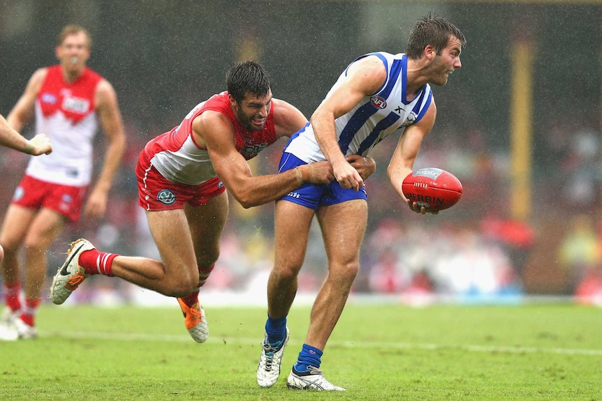 The Kangaroos' Luke McDonald is tackled by Sydney's Tom Derickx at the SCG