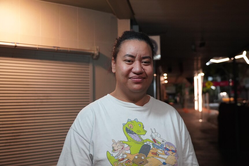 Lorina Sui stands in front of a roller door outside in Alice Springs at night.