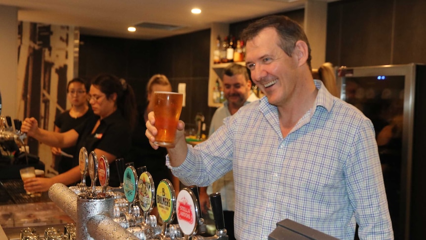 The Northern Territory Chief Minister Michael Gunner holds a beer at a pub.