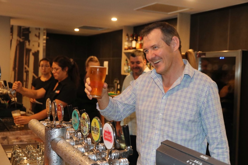 The Northern Territory Chief Minister Michael Gunner holds a beer at a pub.