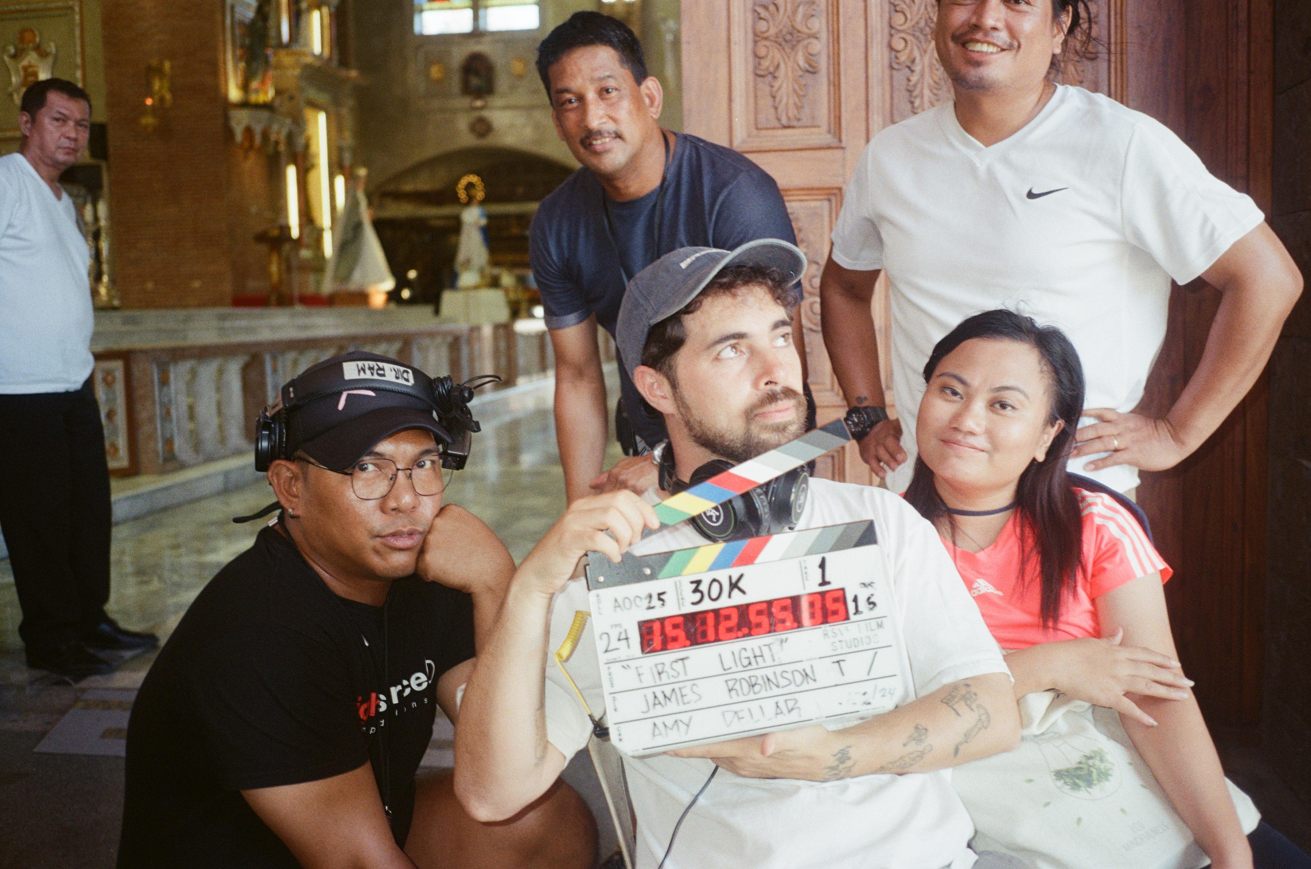 People pose around a man with a clapboard