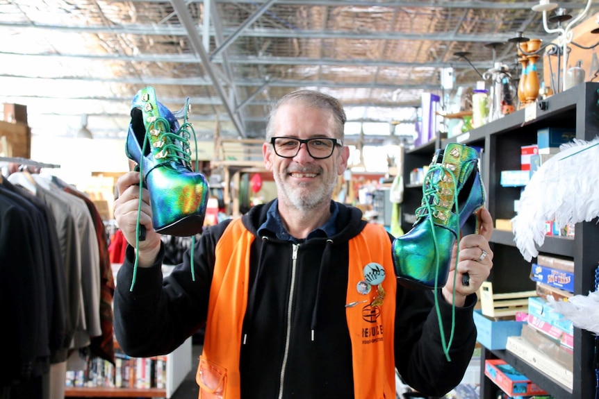 Jason Richards shows off some platform shoes that were  dropped off at the tip shop
