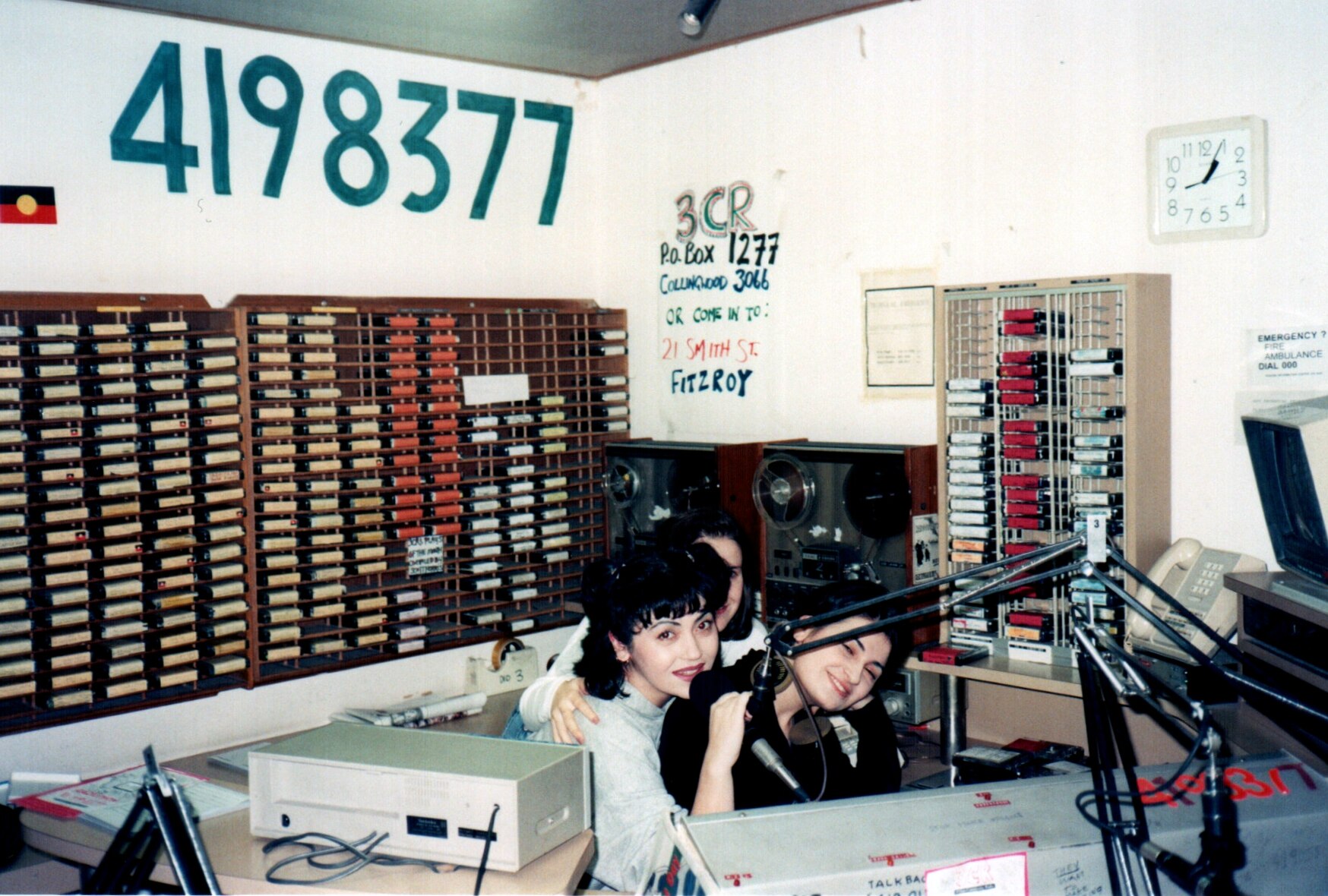 Three young women sit close together in a radio studio